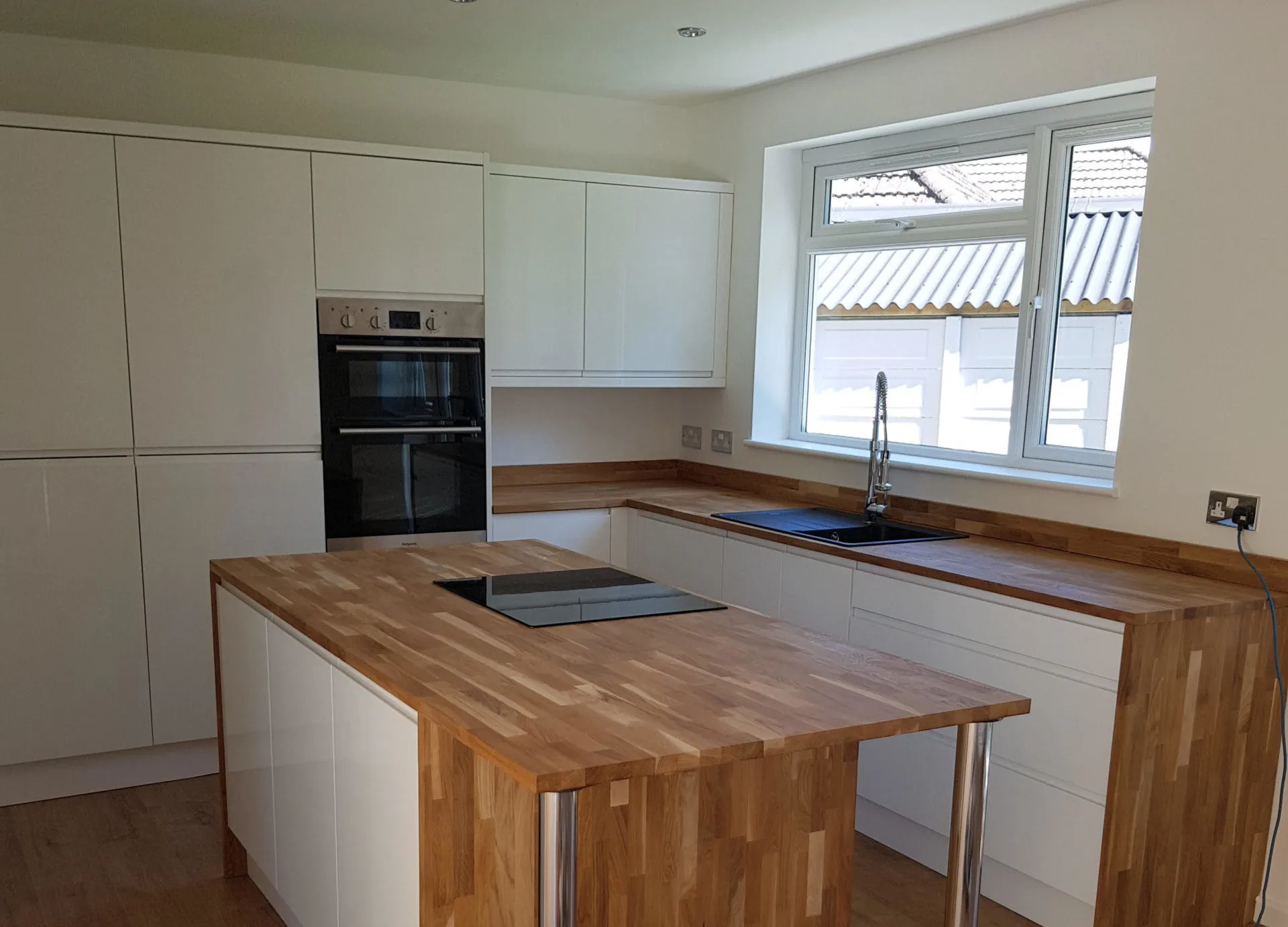 A new light kitchen with an oak worktop island and integrated appliances
