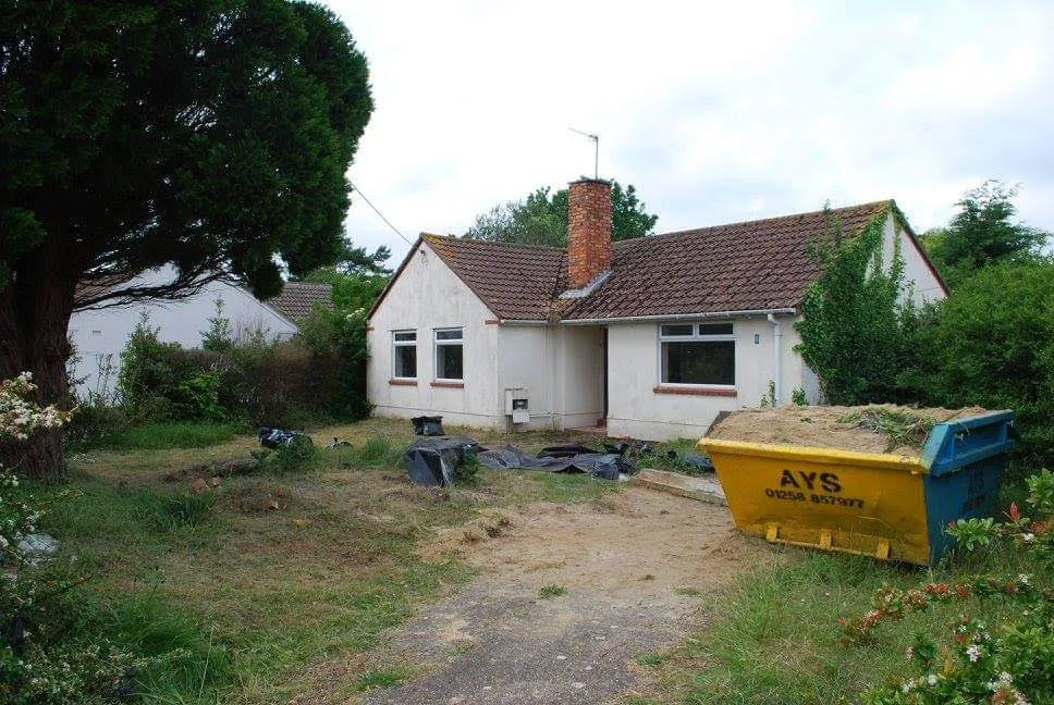 The bungalow before: an overgrown front garden and a skip