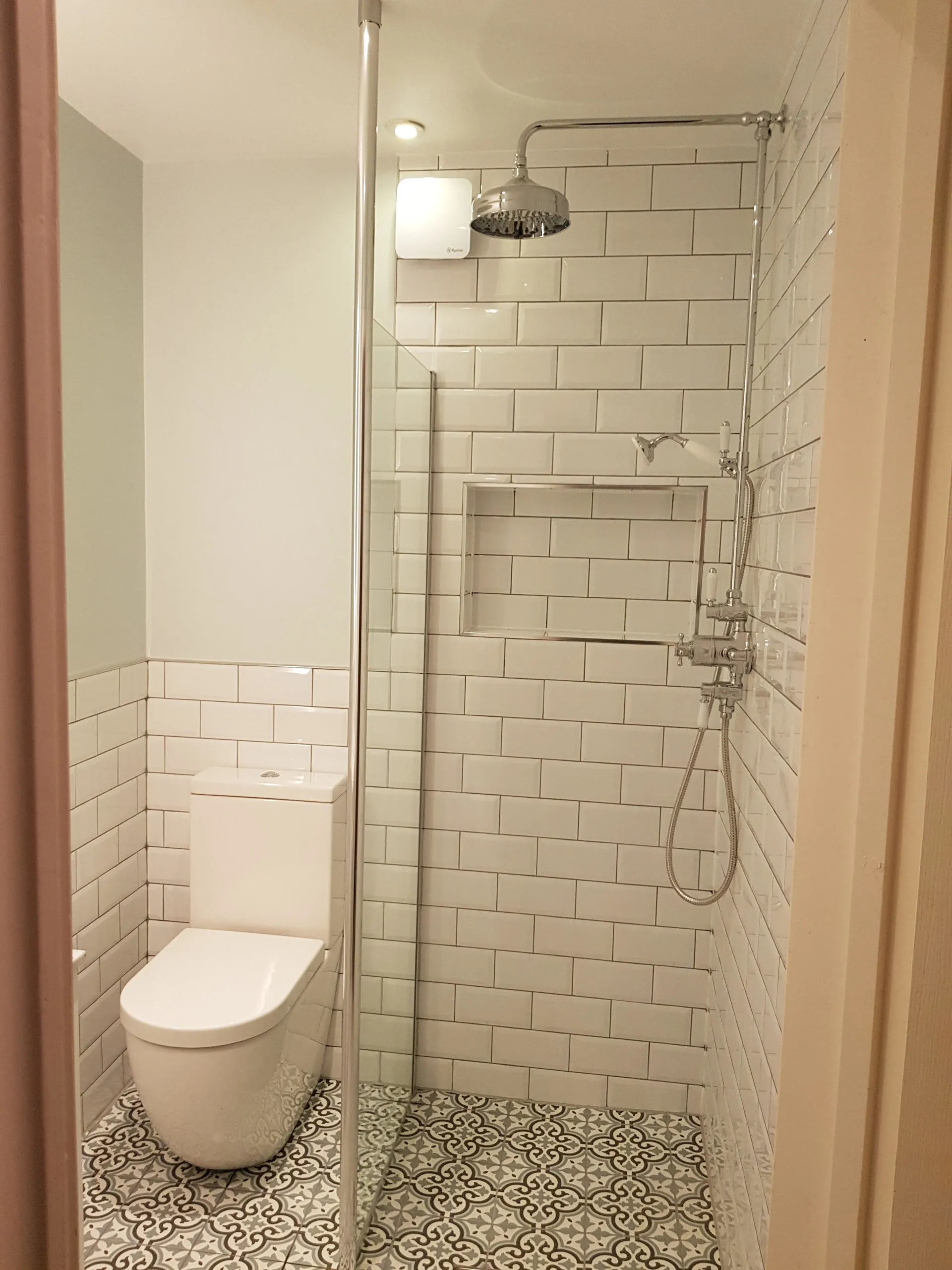 A new shower room with white metro tiles and a patterned floor